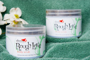 Two jars of body butter sitting on top of a green towel.