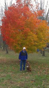 A man standing in front of a tree with fall colors.