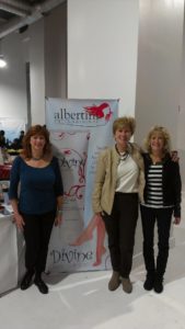 Three women standing in front of a banner.