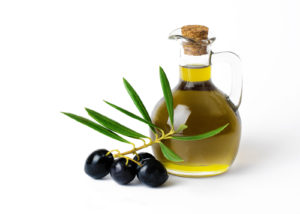 A bottle of olive oil and some olives.