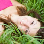 A woman laying in the grass smiling for the camera.